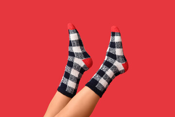 Legs of young woman in warm checkered socks on red background