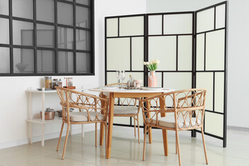 Interior of room with folding screen, shelf unit and dining table