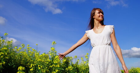 Beautiful woman walking in mustard field on a sunny day