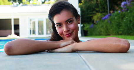 Beautiful woman smiling while leaning over the swimming pool