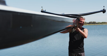 Senior caucasian man carrying a rowing boat
