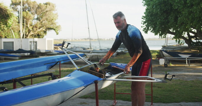 Senior caucasian man preparing rowing boat for the water