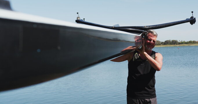 Senior caucasian man carrying a rowing boat