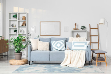 Interior of light living room with grey couch, shelf units and frames
