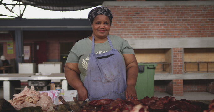Portrait of a happy African female butcher wearing a headscarf in a township workshop, standing next - Powered by Adobe