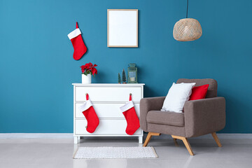 Interior of living room with blank frame, armchair and Christmas plant poinsettia on commode
