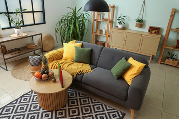 Interior of stylish living room with sofa, candles and fruits for Kwanzaa celebration on table