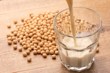 ガラスコップに注がれる豆乳と広がる大豆