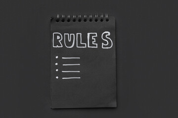 Notebook with blank list of rules on dark background