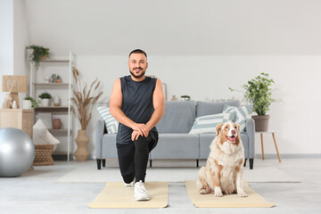 Sporty young man with Australian Shepherd dog training on mats at home