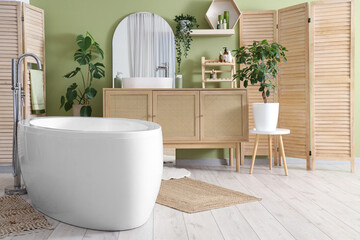 Interior of bathroom with bathtub, sink and wooden folding screen