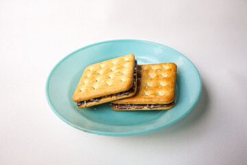 Sandwich biscuits with chocolate filling served in a blue plate on white background