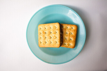 Sandwich biscuits with chocolate filling served in a blue plate on white background