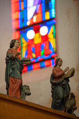 Intricate and detailed religious figures are set against the backdrop of vibrant stained glass within a church