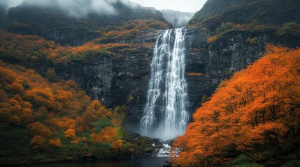 Fototapeta premium A serene waterfall surrounded by vibrant autumn foliage and misty mountains.