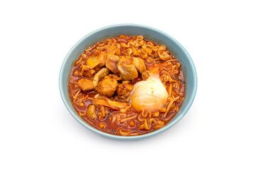 Korean instant noodles with spicy chicken flavor seasoned with kimchi with chicken and soft-boiled eggs in a blue ceramic bowl isolated on white background.
