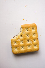Bitten sandwich biscuit with chocolate filling on white background