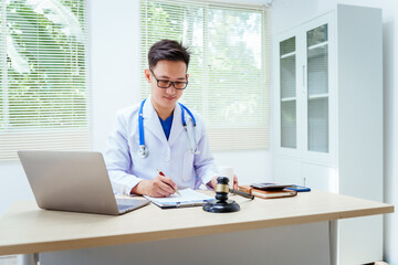 A male doctor sits at a desk, holding a signature pen, discussing medical law. This law safeguards patients and medical institutions during examinations and treatments, ensuring ethical healthcare