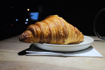 Delicious freshly baked plain croissant on plate in cafe, croissant on white plate