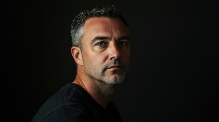 Fototapeta premium A striking portrait of a man against a black background, emphasizing his features with dramatic lighting