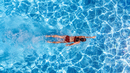 Active girl in swimming pool aerial drone view from above, young woman swims in blue water, tropical vacation, holiday on resort concept