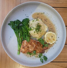 grilled dijon salmon with vegetables on a white plate - on wooden table top