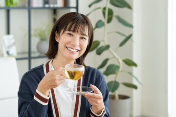 リビングでハーブティーを飲む若い女性