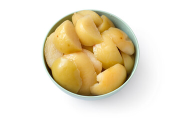 Slices of canned apples in a plate on a white background. A bowl of yellow canned apples.