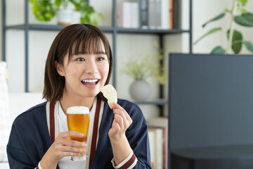 ビールを飲みながらテレビを見る若い女性