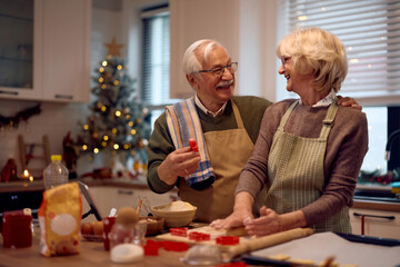 Happy senior couple having fun while baking for Christmas holidays.