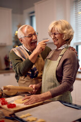 Playful senior couple making a cake for Christmas holidays.