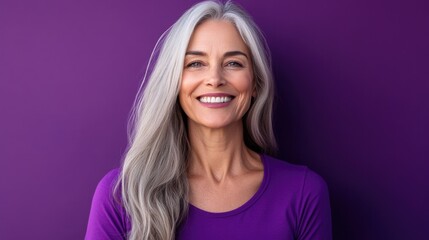 Cheerful beautiful mature woman with a vibrant smile standing against a purple background .Senior businesswoman, 60s grey haired lady professional female manager, leader looking at camera, copy space.