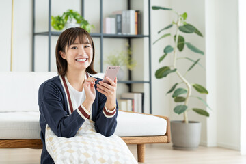 リビングでスマホを見る若い女性