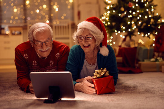 Happy senior couple making video call over touchpad on Christmas Eve.