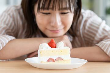 ショートケーキを我慢する若い女性