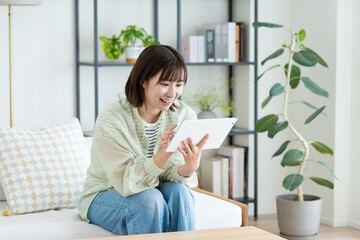 リビングでタブレット端末を使う若い女性