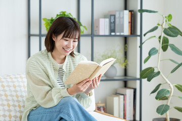 リビングで読書をする若い女性