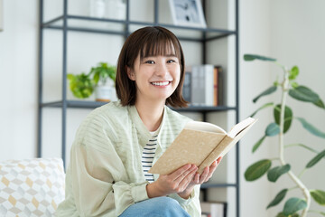 リビングで読書をする若い女性