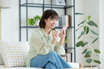 リビングでスマホを使う若い女性