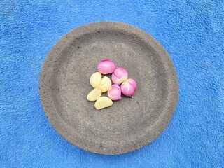 Red onions and garlic are placed on a pestle with a blue cloth background