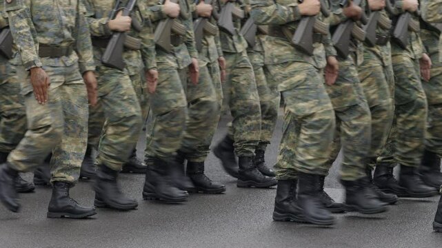 Soldiers with machine guns in hands march in ranks. Trained servicemen show professional skills in handling firearms during festive march to mark Independence Day of Austria