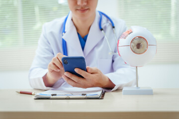 A male doctor wearing glasses sits at a desk in a hospital, explaining eye diseases like glaucoma,...