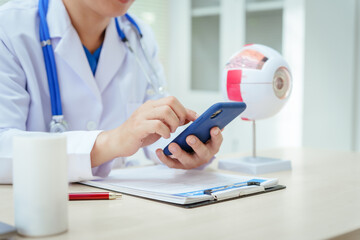 A male doctor wearing glasses sits at a desk in a hospital, explaining eye diseases like glaucoma,...