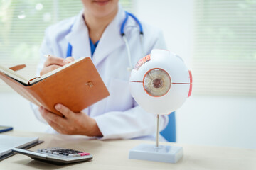 A male doctor wearing glasses sits at a desk in a hospital, explaining eye diseases like glaucoma,...