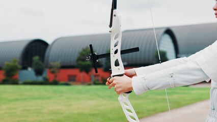 Woman, hands and prepare bow for archery training at academy, outdoor exercise and aim. Female...