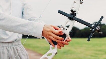 Person, archery and hands at field for sport at shooting practice and training as athlete in Japan. Closeup, target and setup recurve bow or equipment for challenge, tournament and competition