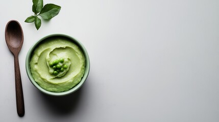Obraz premium Healthy food creamy green pea puree garnished with peas and basil leaves