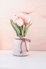 A bouquet of artificial pink tulips in a ceramic vase. A gentle photo in pale pink shades