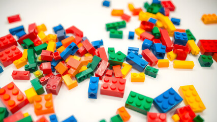Fototapeta premium Plastic building bricks scattered on a white table, vibrant colors, ample space for text on the bottom. Generative AI