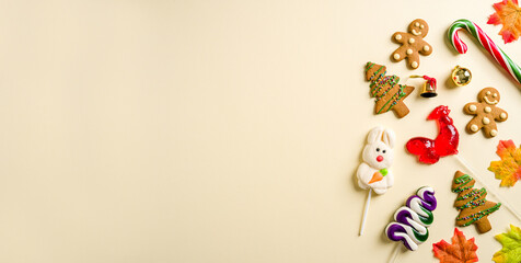 Christmas background with rooster candy, gingerbread cookie and various Christmas decorations on yellow background
